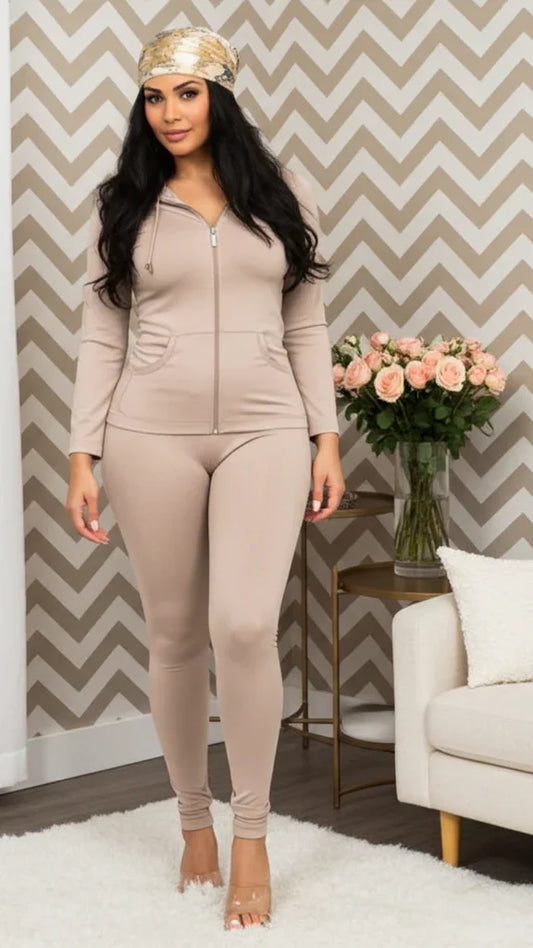 Woman in a beige tracksuit standing in a living room with a chevron patterned wall.