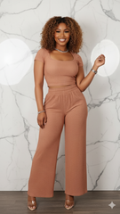 Woman wearing a brown jumpsuit against a marble wall background