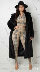 Woman wearing a plaid outfit with a black coat and hat on a white marble background