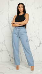 Woman wearing light blue cargo pants and a black top against a white marble background