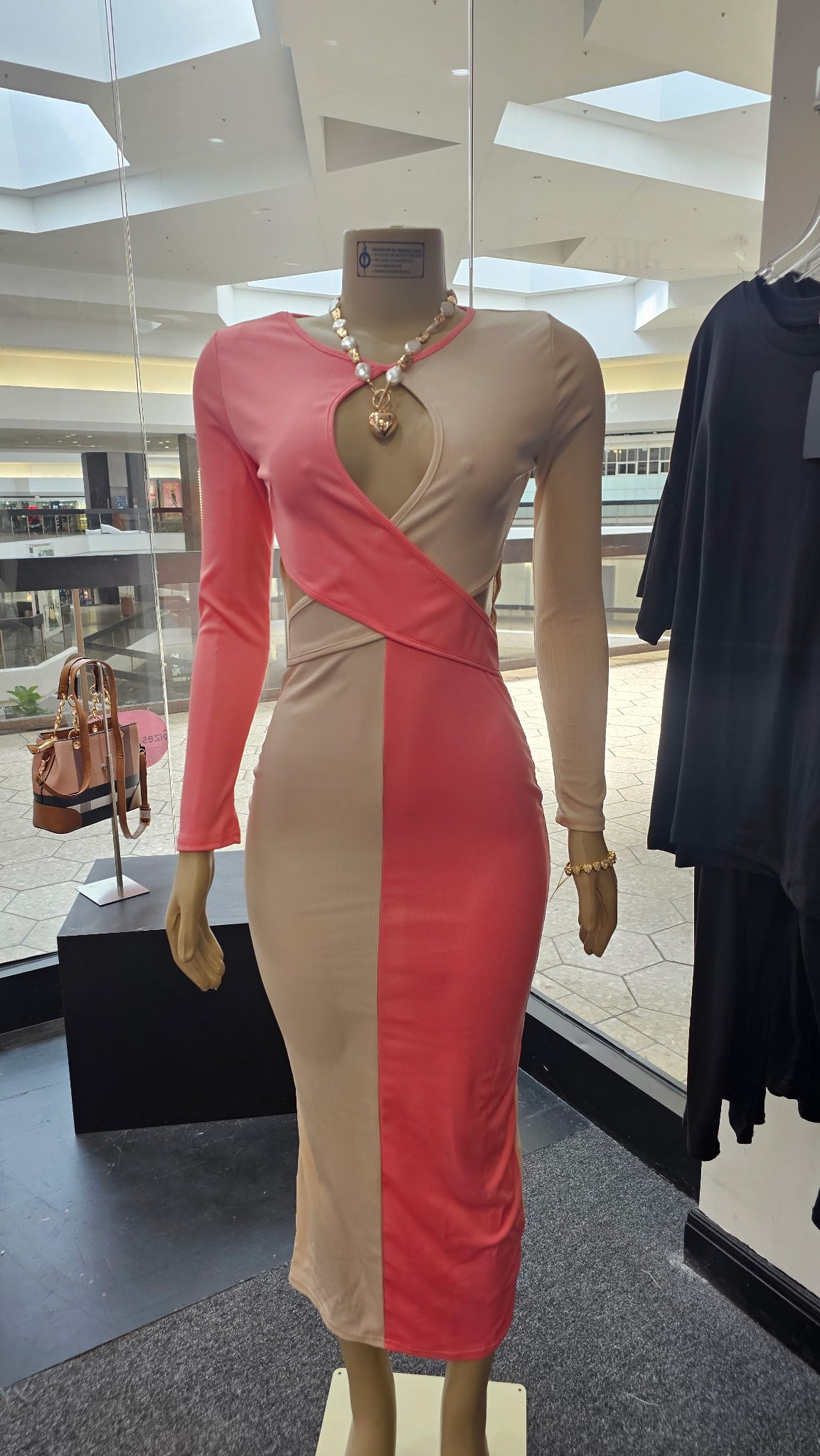 Mannequin wearing a two-tone dress with pink and beige colors in a store setting.
